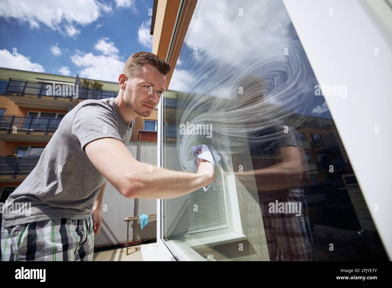 Homme nettoyant la fenêtre avec un chiffon à la maison. Thèmes travaux ménagers et entretien ménager. Banque D'Images