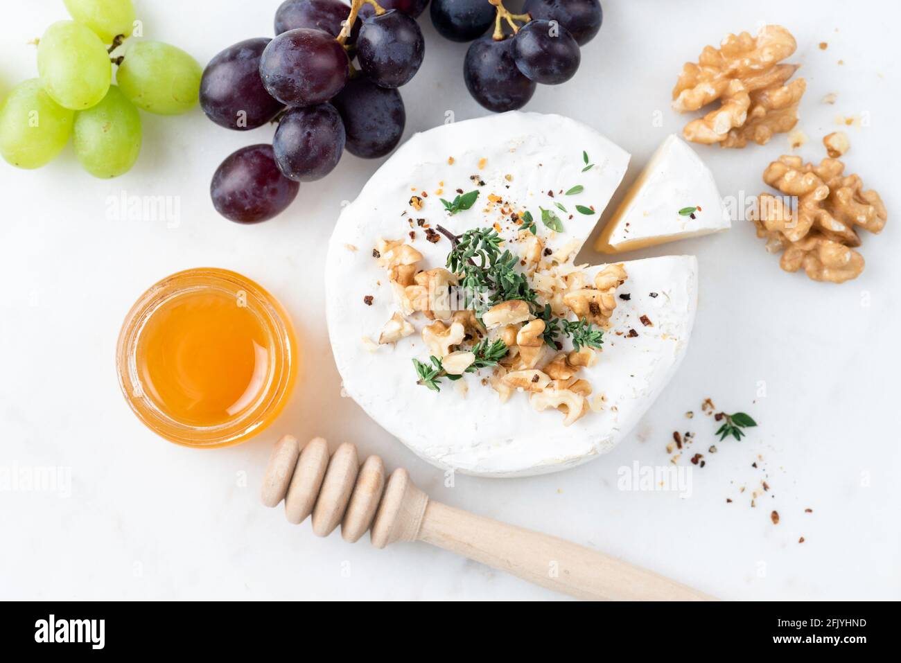 Camembert aux noix, au miel et au raisin sur une planche à fromage en marbre blanc, apéritif avec vue sur la table Banque D'Images