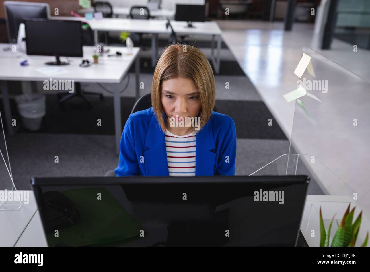 Femme d'affaires asiatique assise au bureau devant l'ordinateur à proximité éternuez sur le bouclier Banque D'Images