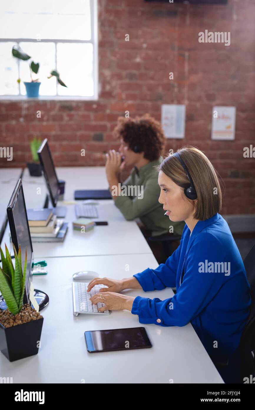 Femme d'affaires asiatique assise devant un ordinateur portant un casque ayant appel vidéo Banque D'Images