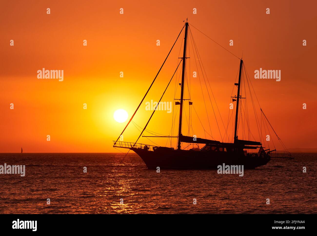Vue rapprochée de la silhouette du bateau à voile avec voiles contre le  soleil au coucher du soleil, reflet du soleil sur les eaux de mer. Paysage  marin romantique Photo Stock -