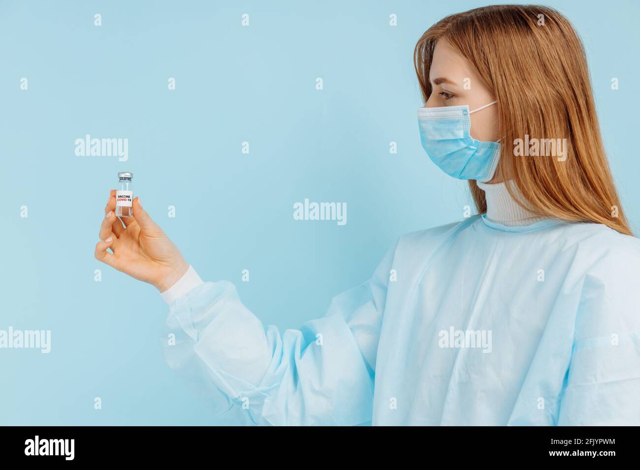 Médecin femme dans un masque médical sur son visage, tient un vaccin contre la grippe, la rougeole, le coronavirus pour la vaccination contre une épidémie, sur un bac bleu Banque D'Images
