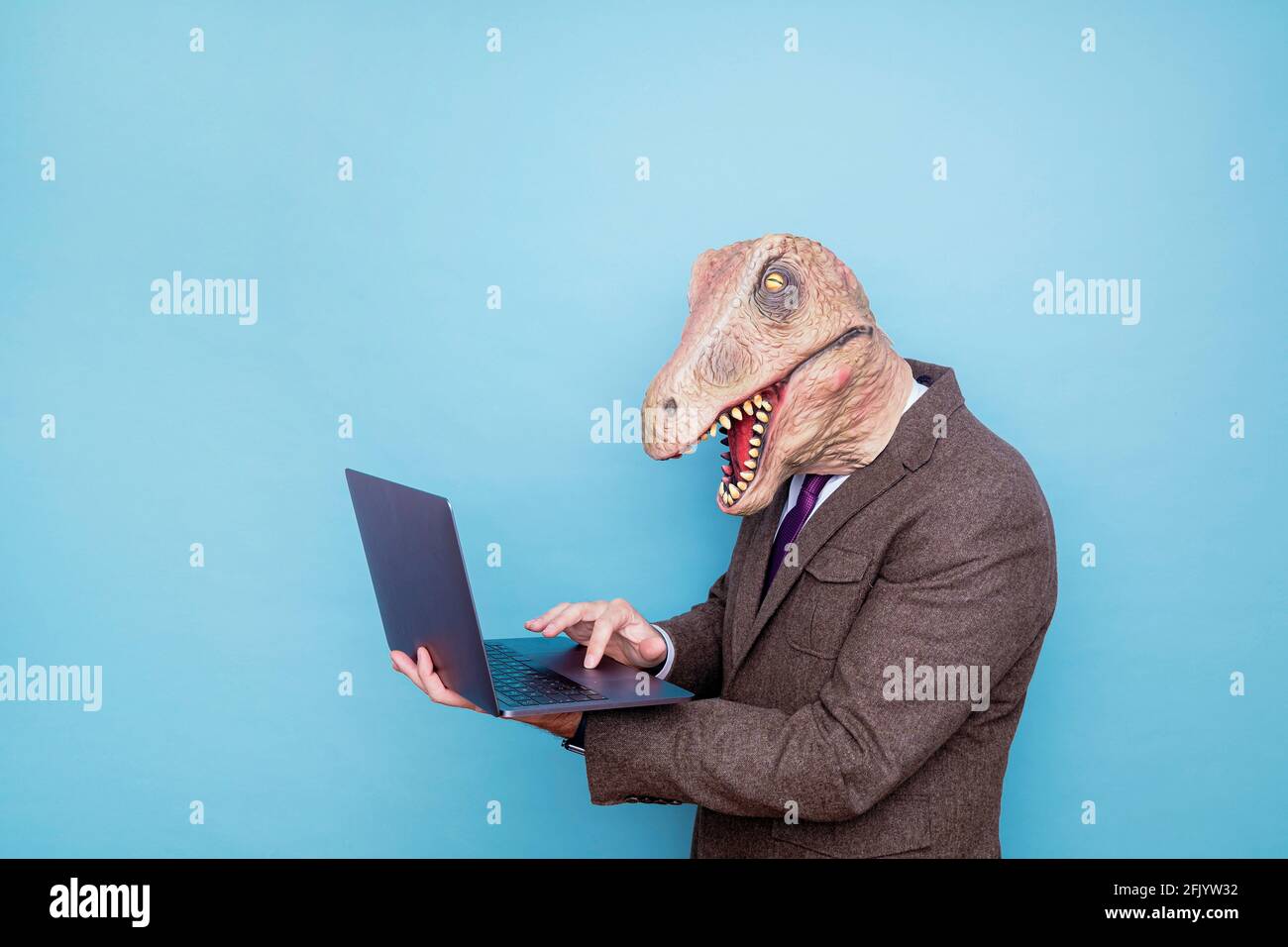 Homme euphorique avec tête de lézard avec ordinateur portable sur fond bleu Banque D'Images