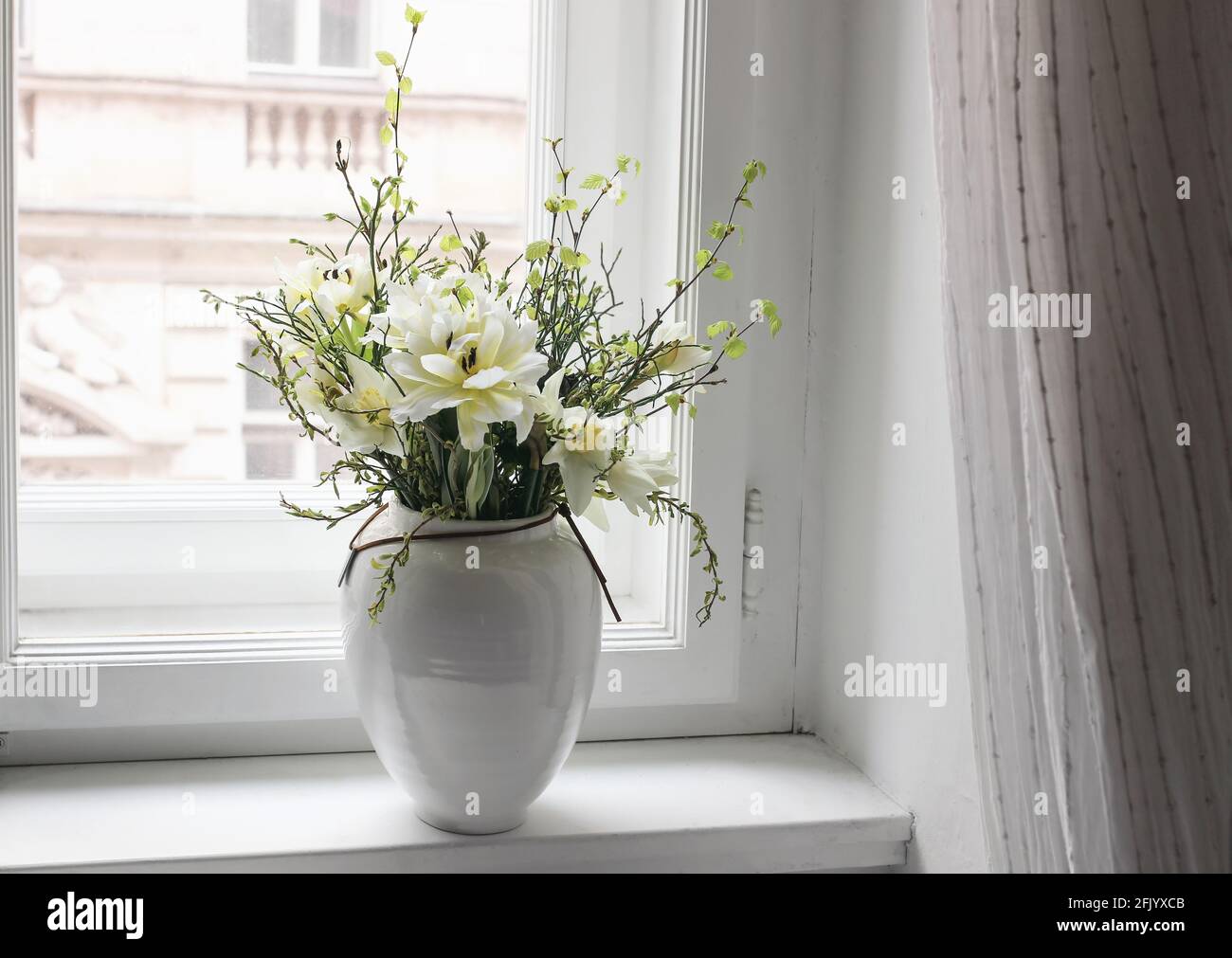 Le printemps de Pâques reste la vie. Bouquet floral sur le rebord de la fenêtre. Tulipes blanches et jaunes, fleurs de jonquilles et branches de bouleau vert et de myrtille Banque D'Images