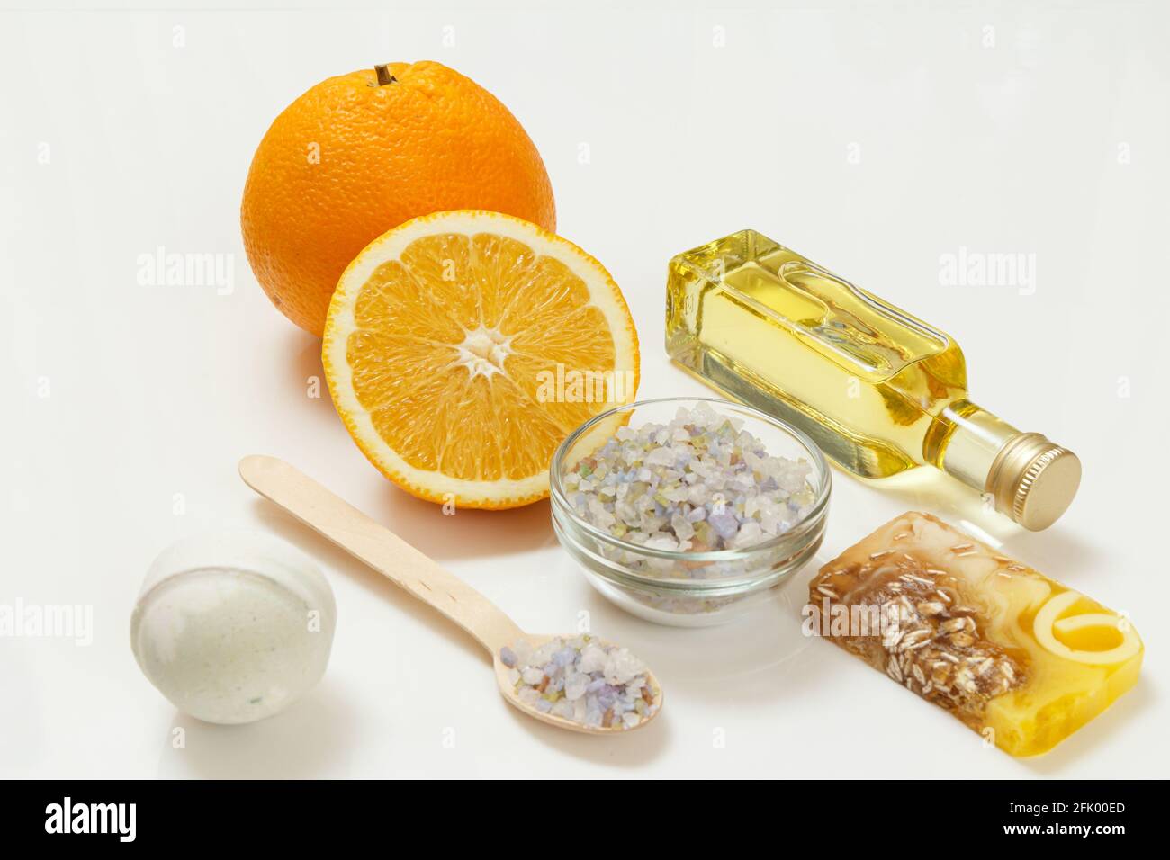Couper l'orange avec un tout, une bouteille avec de l'huile  d'aromathérapie, du savon maison, une bombe de bain, un bol en verre et une  cuillère en bois avec du sel de mer