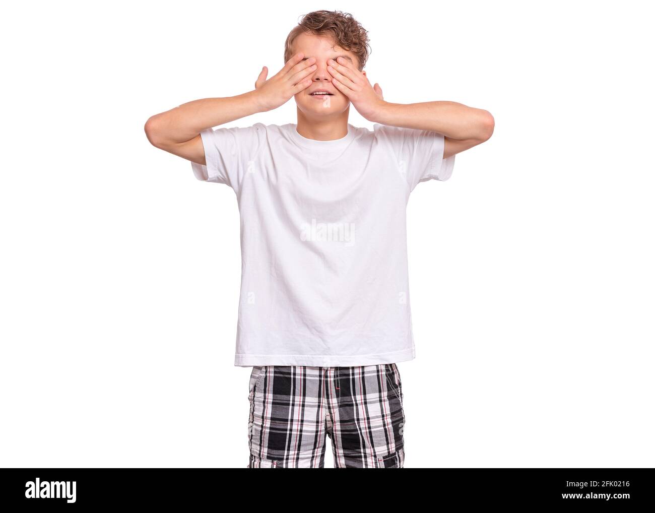 Beau garçon adolescent avec une expression triste couvrant le visage avec les mains en pleurant, isolé sur fond blanc Banque D'Images