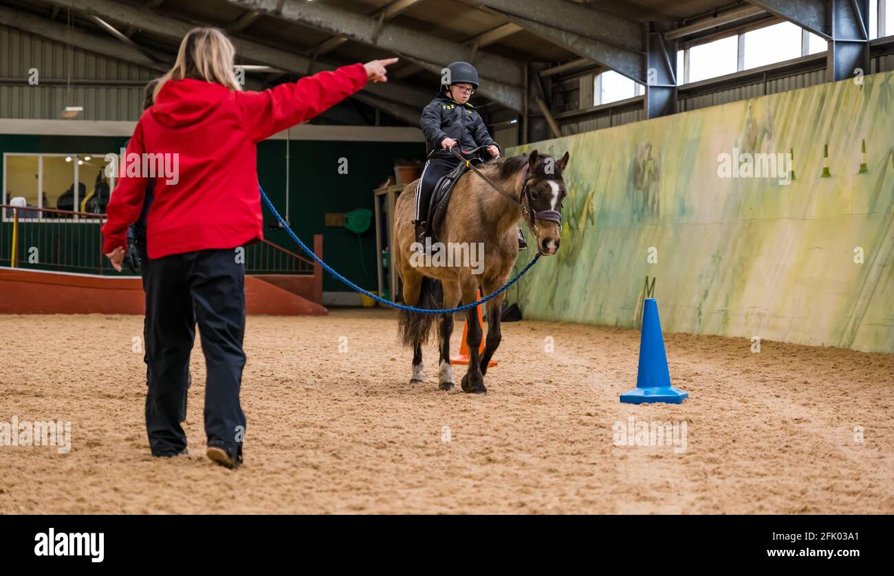 East Lothian, Écosse, Royaume-Uni, 27 avril 2021. Muirfield Riding Therapy rouvre: L'organisme de bienfaisance accueille ses premiers jeunes pour leur séance de thérapie avec des restrictions de verrouillage assouplies. En raison de restrictions continues, seuls les clients plus mobiles peuvent être pris en charge pour le moment. Photo: Fin, 10 ans, un élève à l'école primaire de yester sur son cheval de thérapie Briony instruit par l'entraîneur Shirley Duff apprendre à contrôler les rênes et à diriger le cheval Banque D'Images