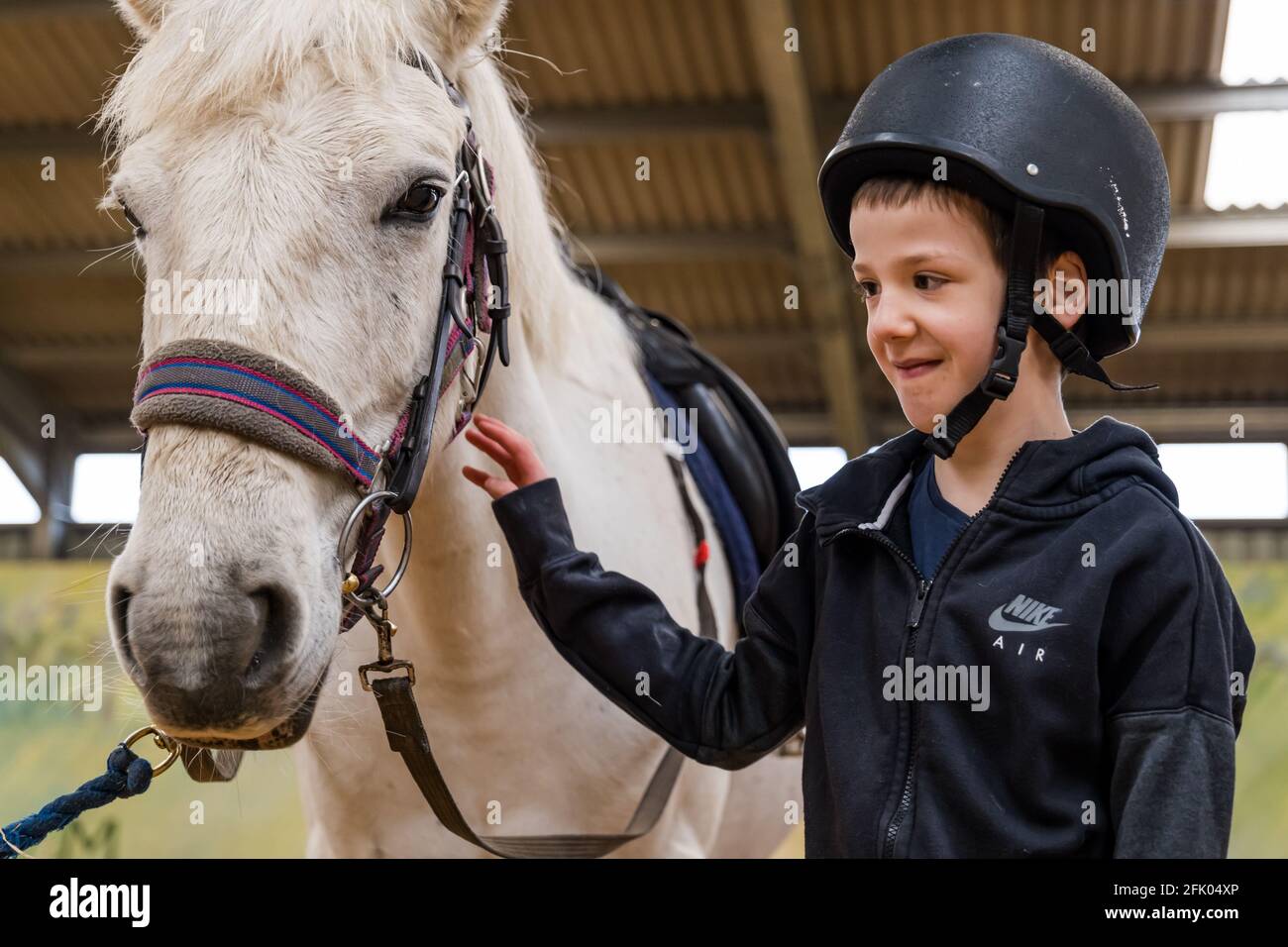 East Lothian, Écosse, Royaume-Uni, 27 avril 2021. Muirfield Riding Therapy rouvre: L'organisme de bienfaisance accueille ses premiers jeunes pour leur séance de thérapie avec des restrictions de verrouillage assouplies. En raison de restrictions continues, seuls les clients plus mobiles peuvent être pris en charge pour le moment. Photo : Nathan, âgé de 10 ans, élève de l'école primaire de yester avec son cheval de thérapie Johnny Banque D'Images