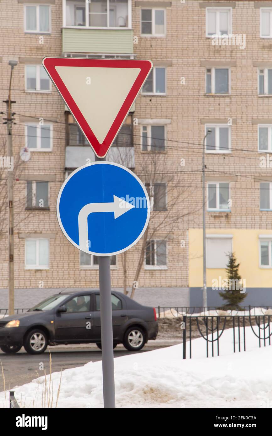 Les panneaux de signalisation signifient aller et tourner à droite seulement. Sur le fond d'une route et d'un bâtiment résidentiel. C'est l'hiver dans la ville, la neige blanche se trouve dans la rue. Banque D'Images