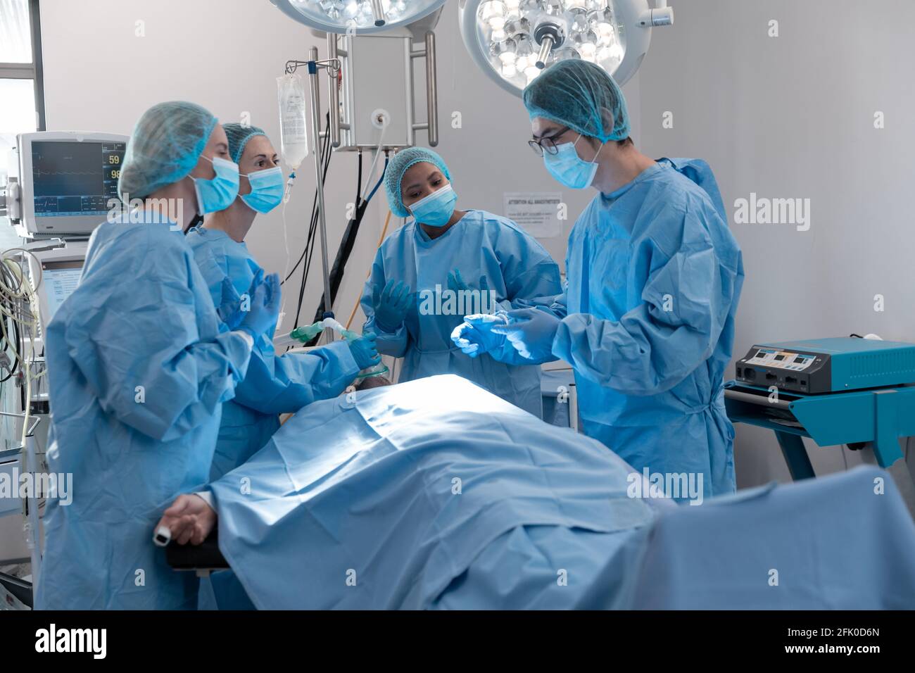 Divers groupes de chirurgiens masculins et féminins dans le bloc opératoire port de masques de chirurgie Banque D'Images