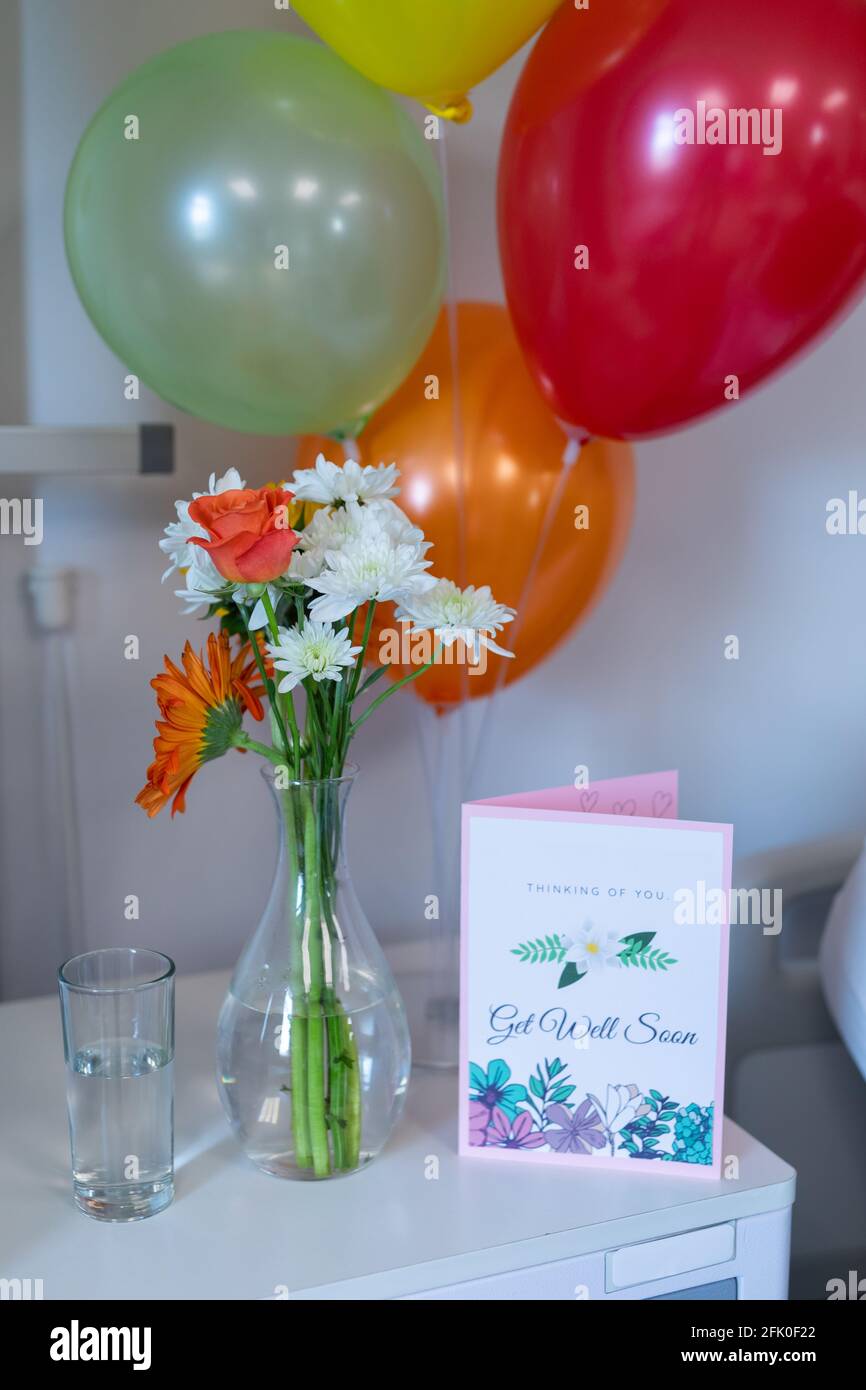 Fleurs dans un vase, carte de puits et ballons sur une table de chevet dans le service pour enfants d'un hôpital Banque D'Images