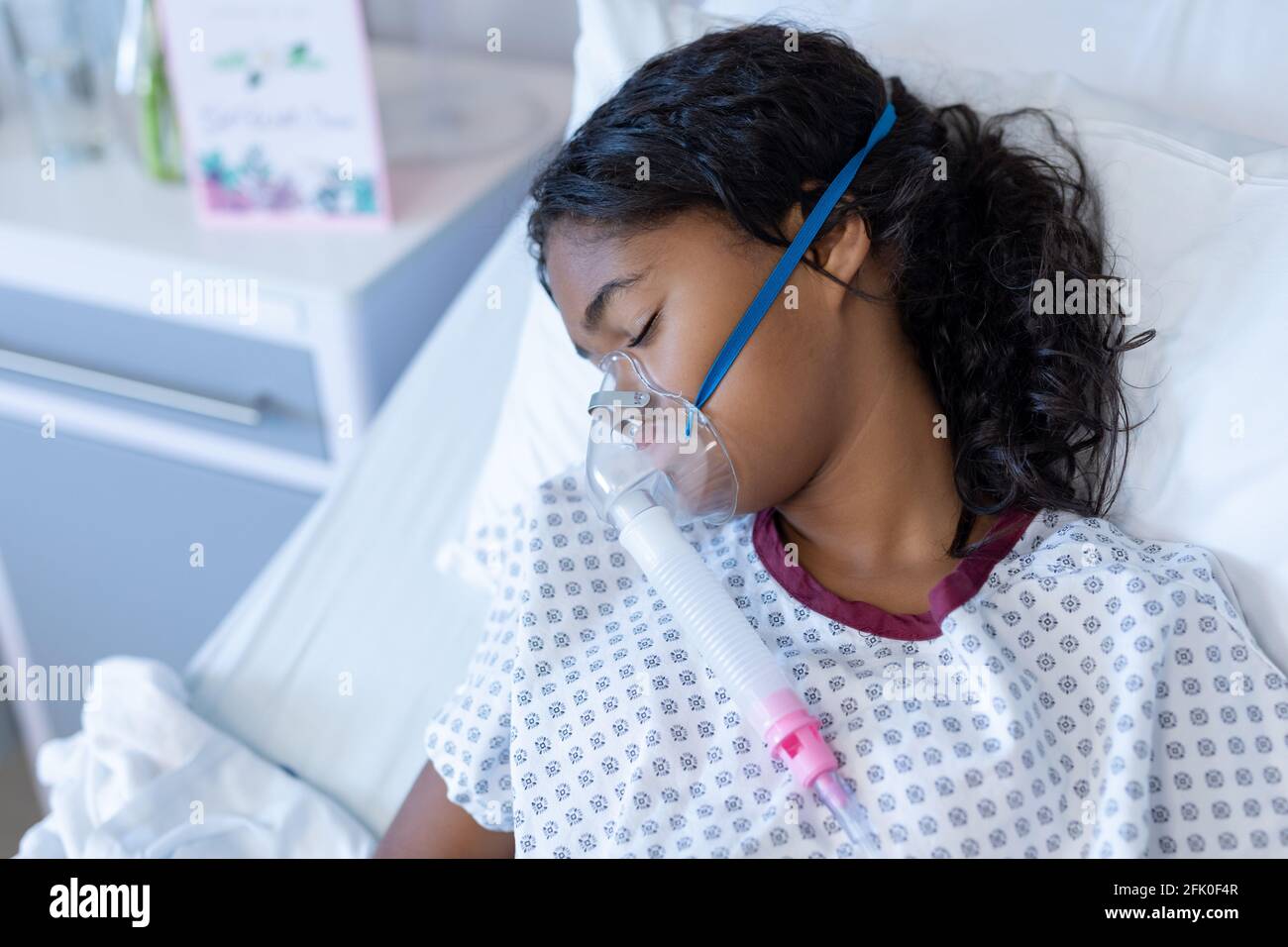 Fille de race mixte malade endormi dans le lit d'hôpital portant de l'oxygène masque ventilateur Banque D'Images
