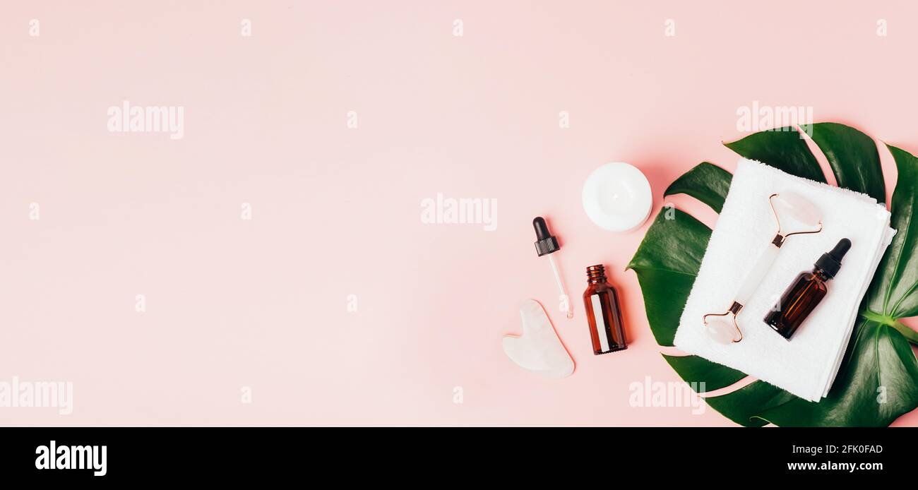 Composition spa sur fond rose pastel. Cosmétiques naturels bio bouteille d'huile, crème, argile, sel, outil de massage gua sha accessoires plan Banque D'Images