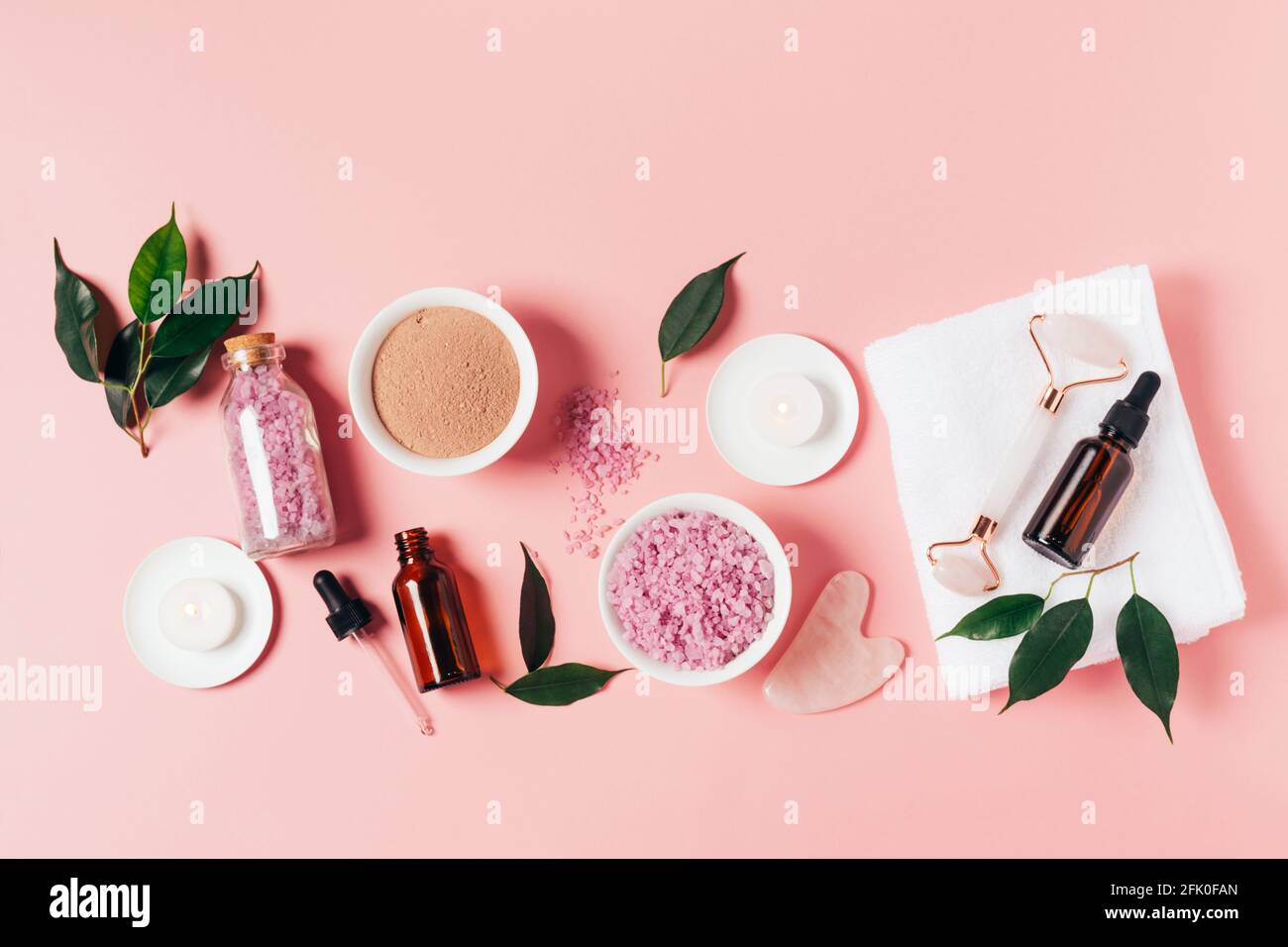 Composition spa sur fond rose pastel. Cosmétiques naturels bio bouteille d'huile, crème, argile, sel, outil de massage gua sha accessoires plan Banque D'Images