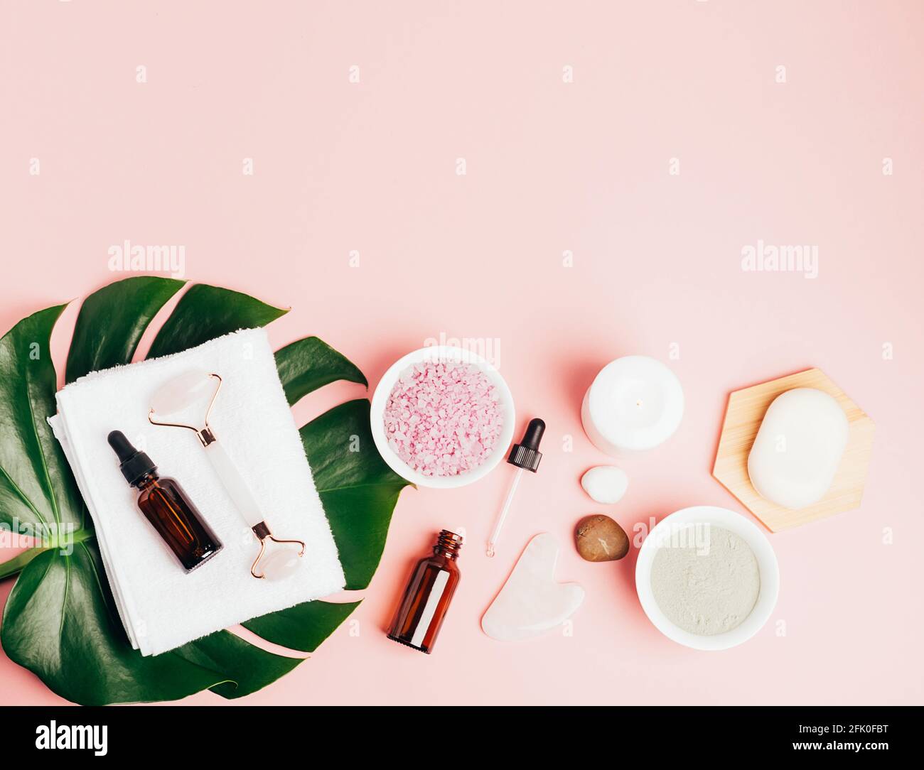 Composition spa sur fond rose pastel. Cosmétiques naturels bio bouteille d'huile, crème, argile, sel, outil de massage gua sha accessoires plan Banque D'Images