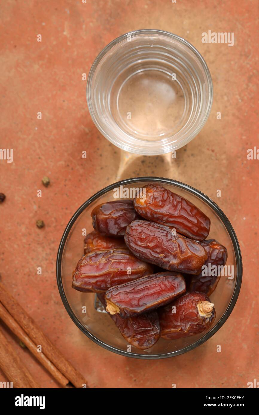 Dattes séchées, ramadan dattes séchées placées dans un bol en verre avec un verre d'eau potable pure placé sur une texture en bois, foyer sélectif. Banque D'Images