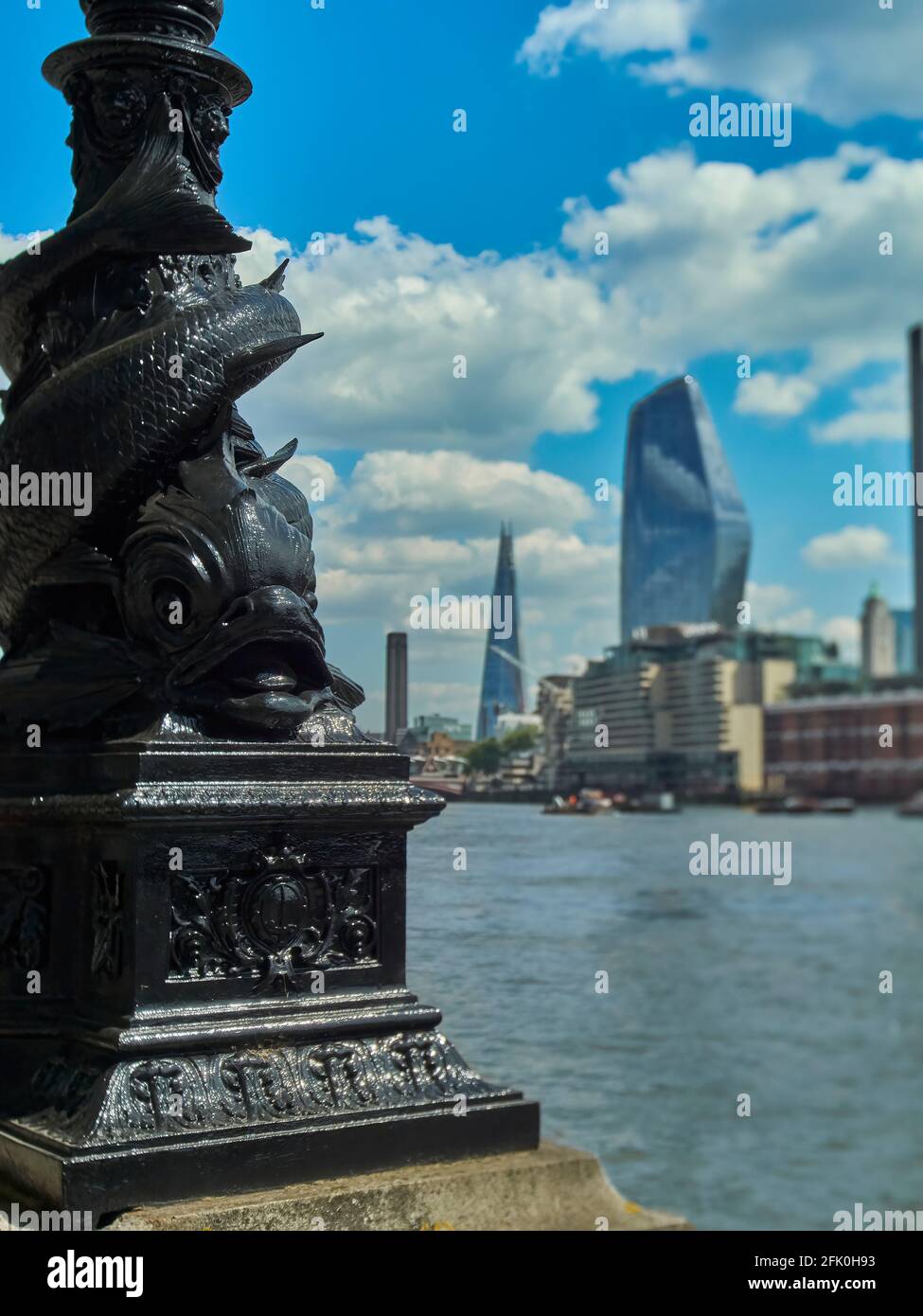 Vue sur la Tamise depuis le Victoria Embankment, concentrée sur des pièces de fer ornementales en premier plan et regardant les gratte-ciels de la rive sud Banque D'Images