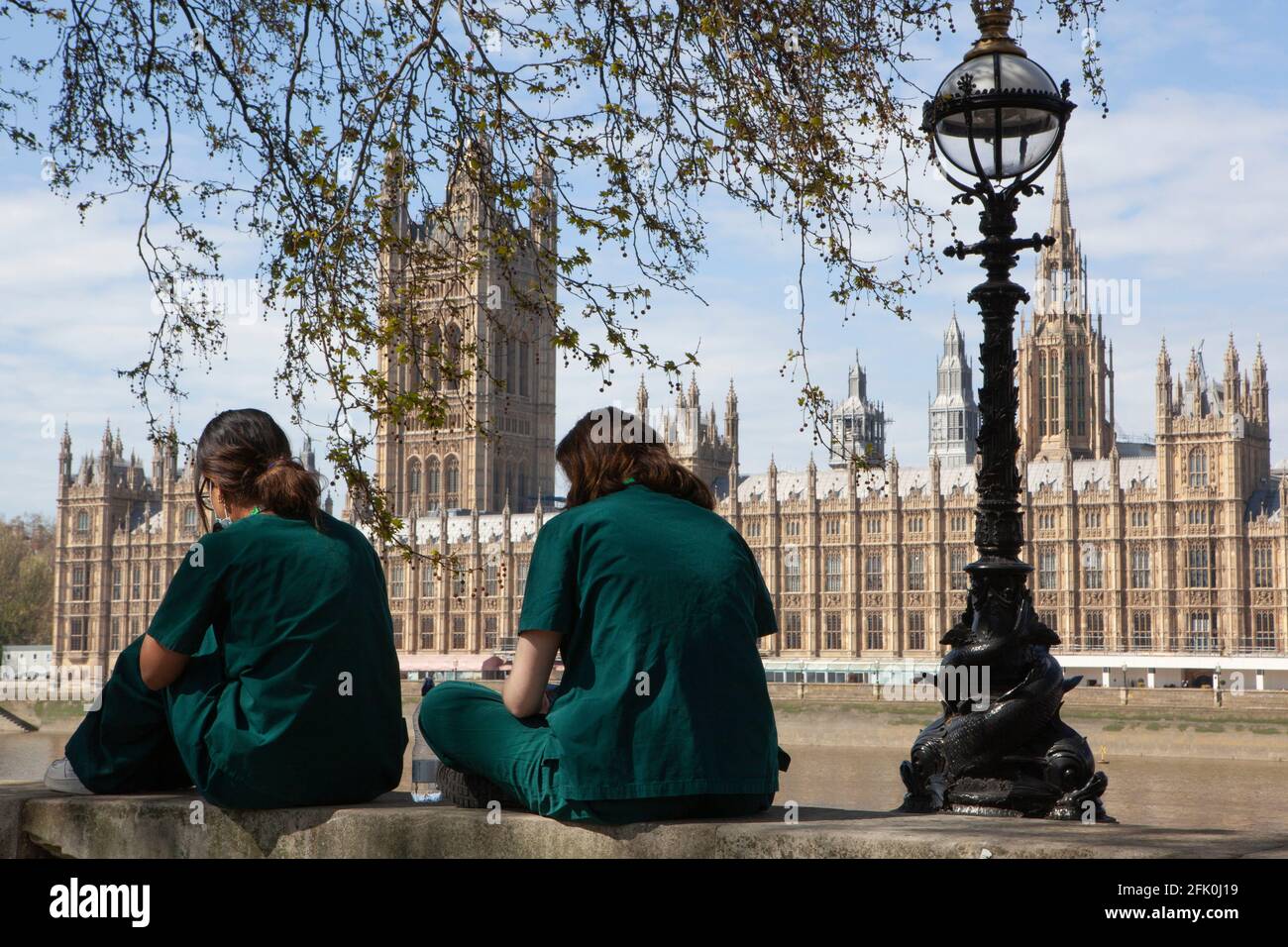 Londres, Royaume-Uni, 27 avril 2021 : les médecins étudiants Charlie et Surina prennent une pause au-dessus du mur commémoratif national Covid alors que le Premier ministre Boris Johnson est toujours accusé d'avoir préféré que les « corps s'accumulent » plutôt que d'avoir un troisième verrouillage. Avec un coeur dessiné pour chacun des plus de 150,000 personnes qui sont mortes dans la pandémie de coronavirus au Royaume-Uni, le mémorial s'étend le long du mur de l'hôpital St Thomas, en face du Parlement sur la rive opposée de la Tamise. Anna Watson/Alay Live News Banque D'Images