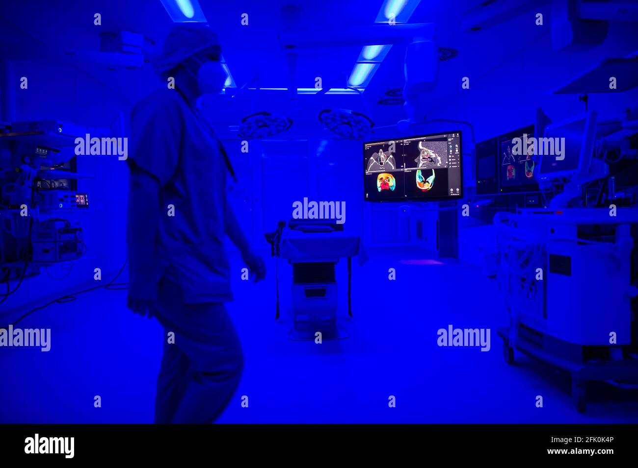 Essen, Allemagne. 27 avril 2021. Une image tomographique d'un crâne facial est visible dans la salle d'opération ORL de l'hôpital universitaire, tandis que la lumière bleue illumine la salle et un assistant chirurgical se promène dans la salle. À l'aide de la lumière bleue, les vaisseaux sanguins peuvent être mieux visualisés en peropératoire. La nouvelle construction de l'aile du théâtre d'opération pour les opérations Eye et ENT a coûté près de 70 millions d'euros. Selon l'hôpital universitaire, ce sont actuellement les salles d'opération les plus modernes d'Allemagne et d'Europe. Credit: Jonas Güttler/dpa/Alay Live News Banque D'Images