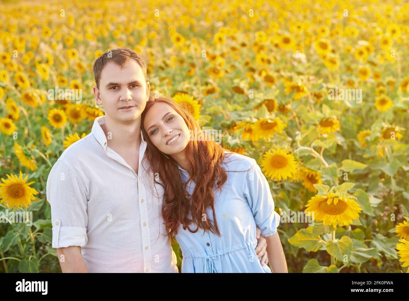 Un couple joyeux et souriant dans un champ de tournesols. Le concept d'amour, de respect mutuel et de bonnes relations. Banque D'Images