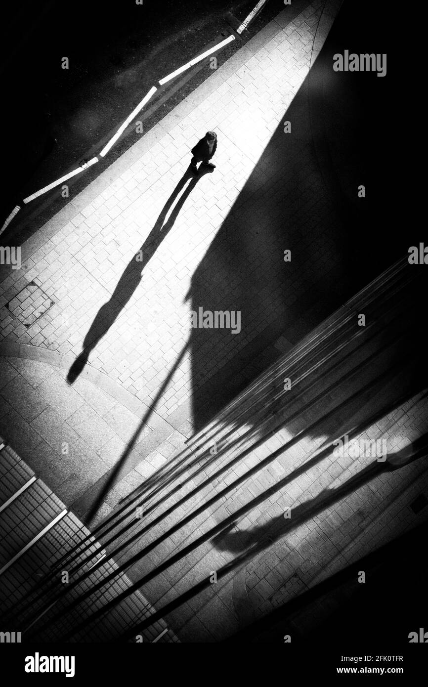 Un homme s'arrête entre les ombres au pied du Shard à Londres. Banque D'Images
