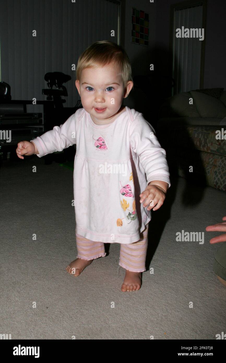Premiers pas d'une fille de 9 mois apprenant à marcher. Banque D'Images