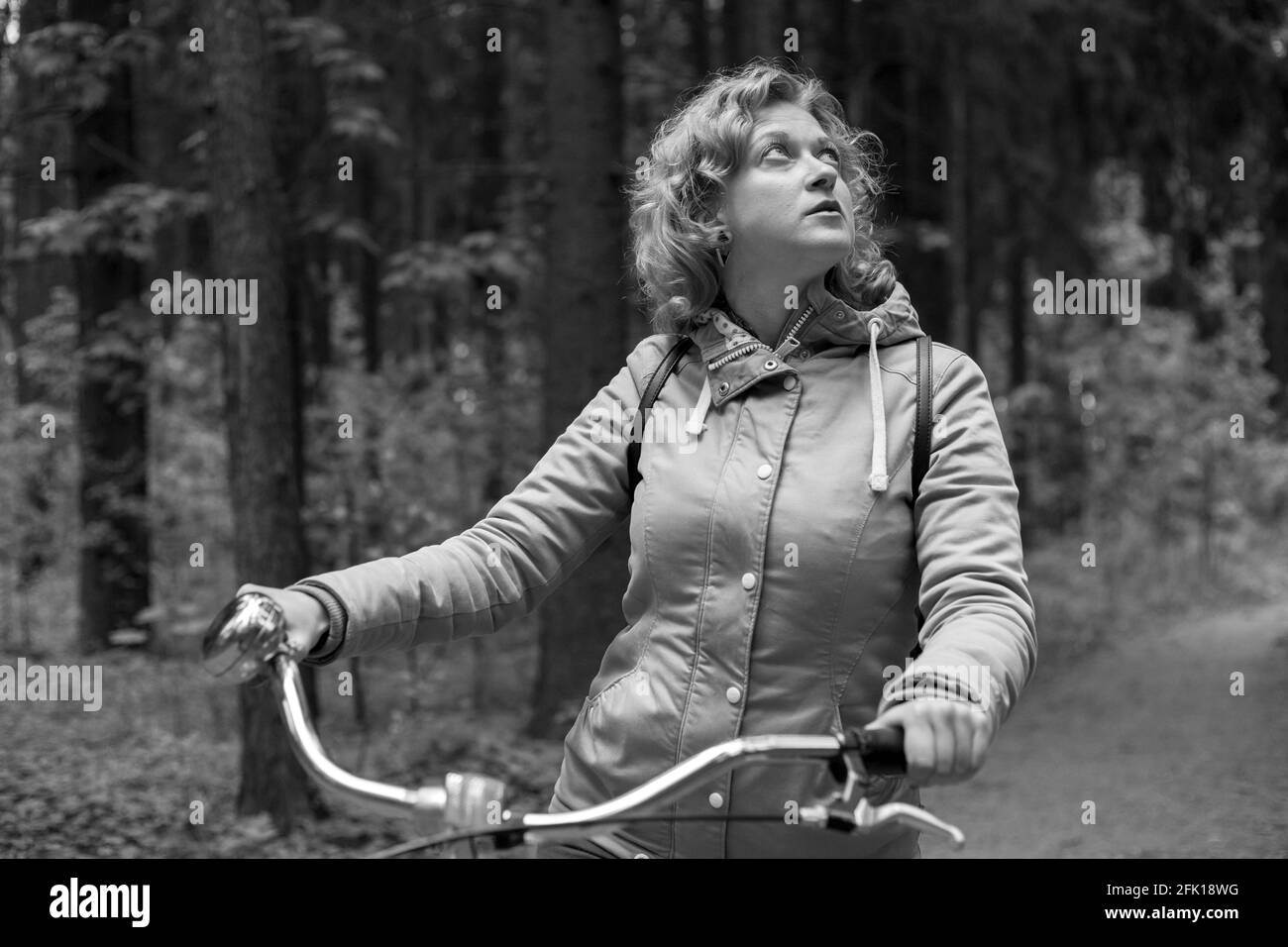 Femme blonde avec vélo dans les bois. Photo en noir et blanc. Banque D'Images