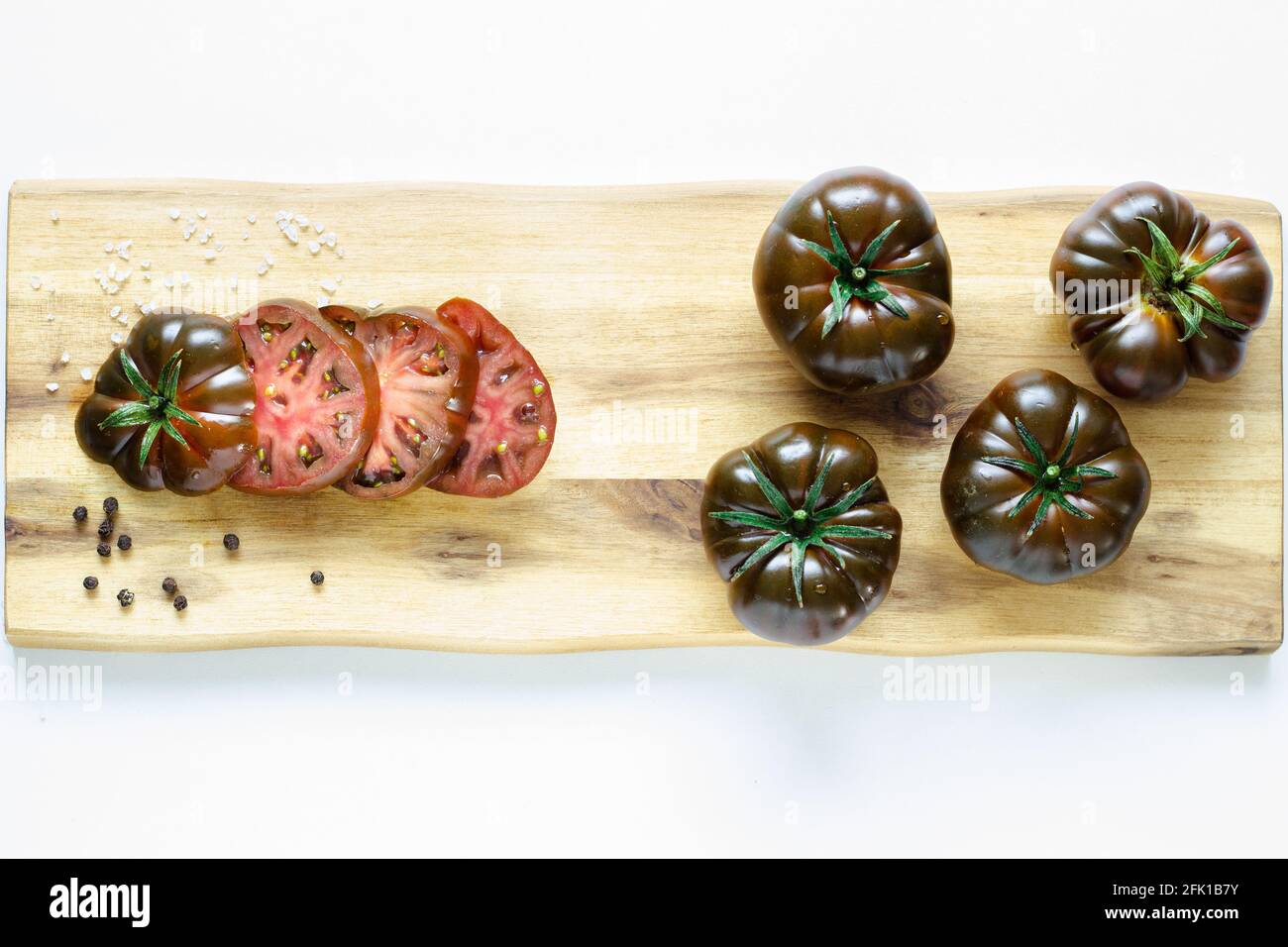 Tomates rouges foncé sur planche à découper en bois avec espace de copie sur fond clair; découpe de tomates; préparation de la cuisine; préparation de la salade Banque D'Images