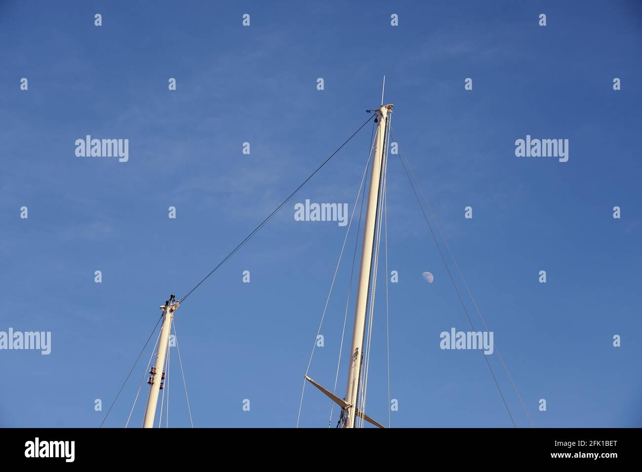 Les mâts du yacht contre le ciel bleu avec la lune. Banque D'Images