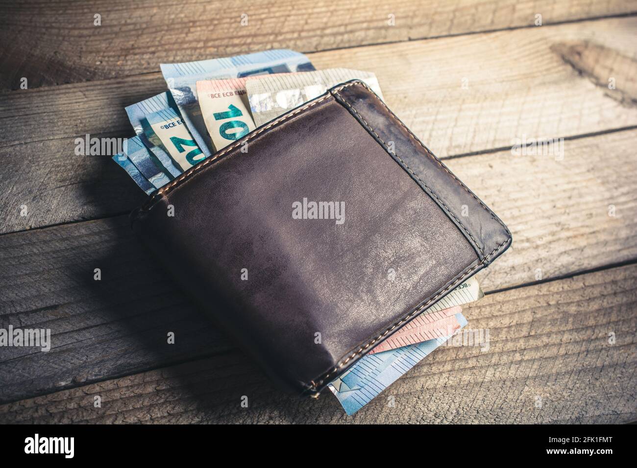 Certains billets en euros sortent d'UN portefeuille en cuir marron Sur UNE planche en bois avec un angle de vue élevé Banque D'Images