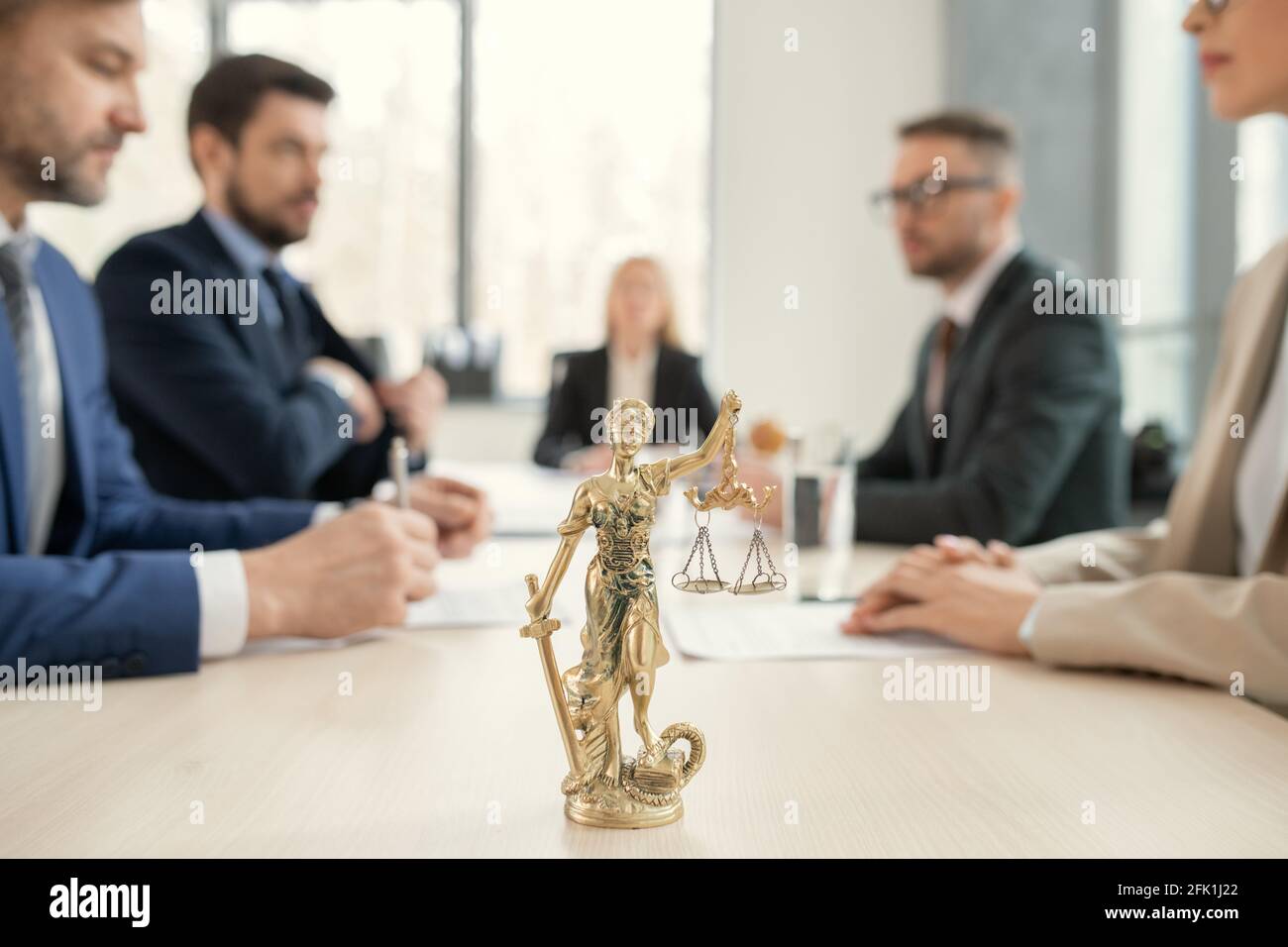 Concentrez-vous sur les themis dorés avec des échelles de justice et de Sward placés sur la table des avocats, des collègues assis les uns en face des autres en arrière-plan Banque D'Images