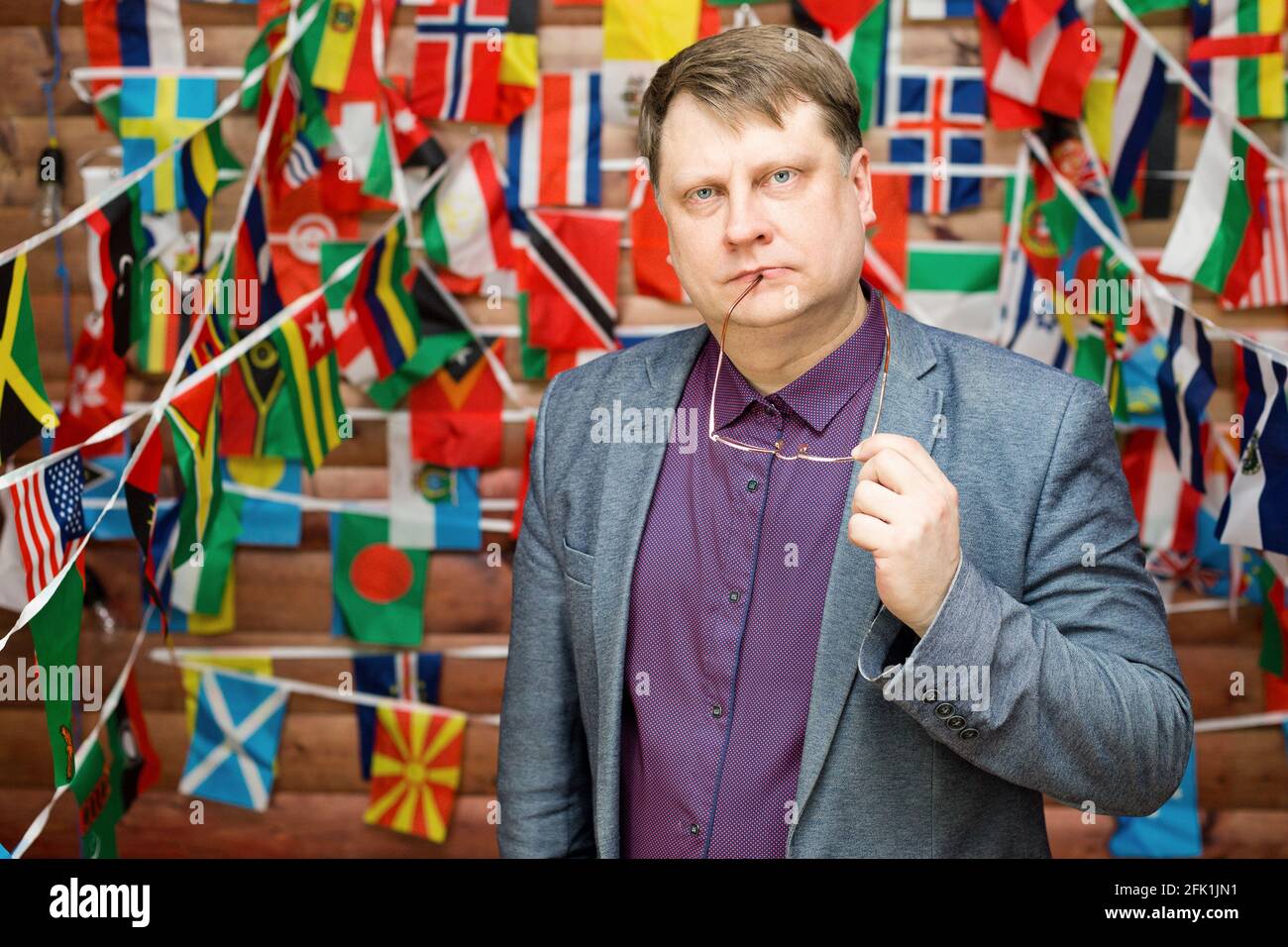 Homme adulte sérieux avec des lunettes dans la main contre le arrière-plan du drapeau de pays Banque D'Images