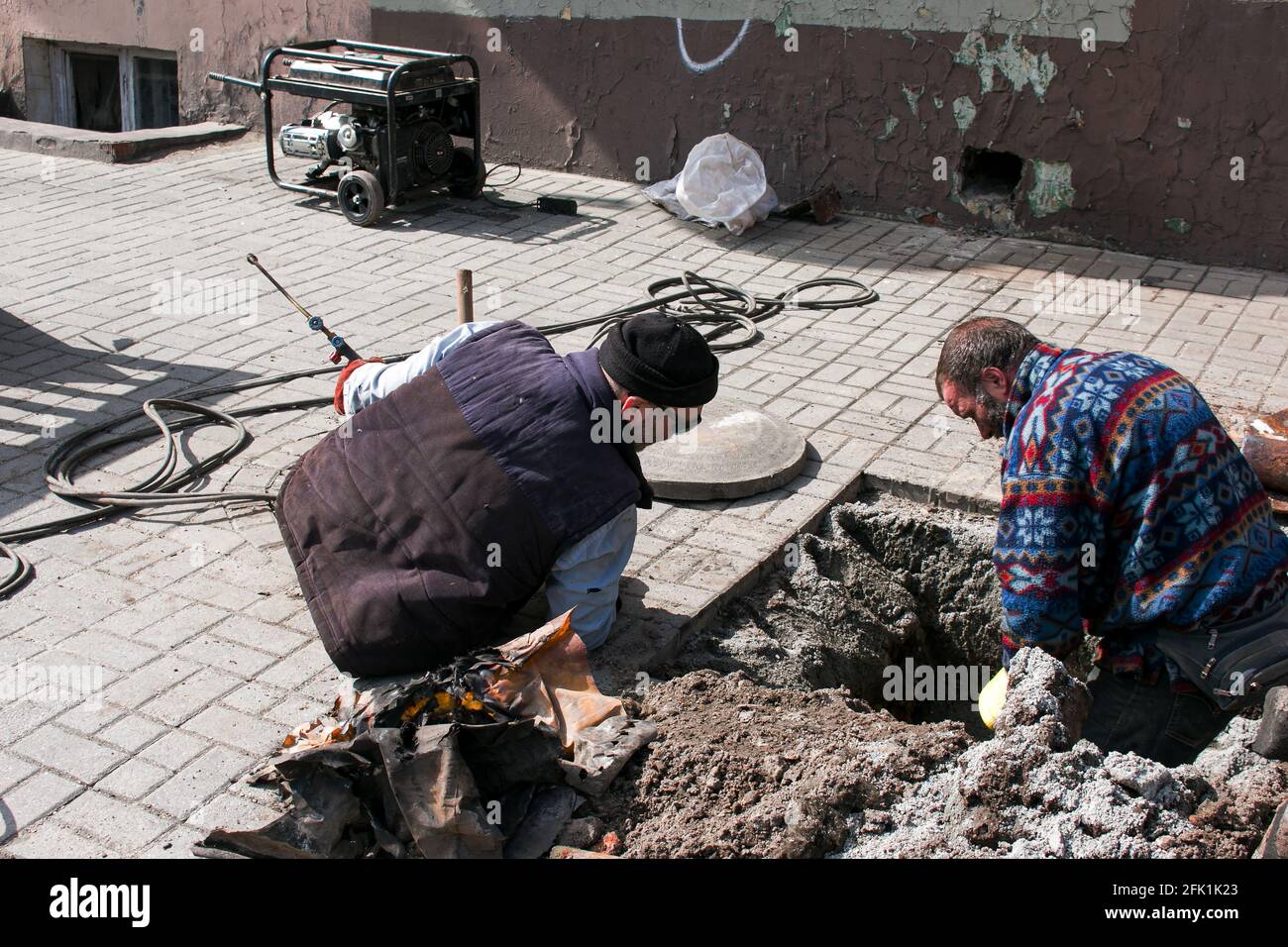 Dnepropetrovsk, Ukraine - 03.26.2021: Les travailleurs des services de distribution d'eau ouvrent un ancien trou d'homme et remplacent les vieux tuyaux rouillés par de nouveaux. Banque D'Images