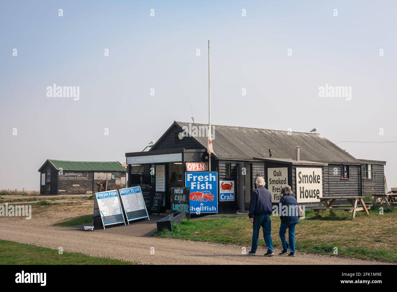 Poissons du Suffolk d'Aldeburgh, vue sur les personnes marchant sur le chemin du front de mer à côté des cabanes de poissons frais situées le long de la plage à Aldeburgh, Suffolk, Royaume-Uni. Banque D'Images