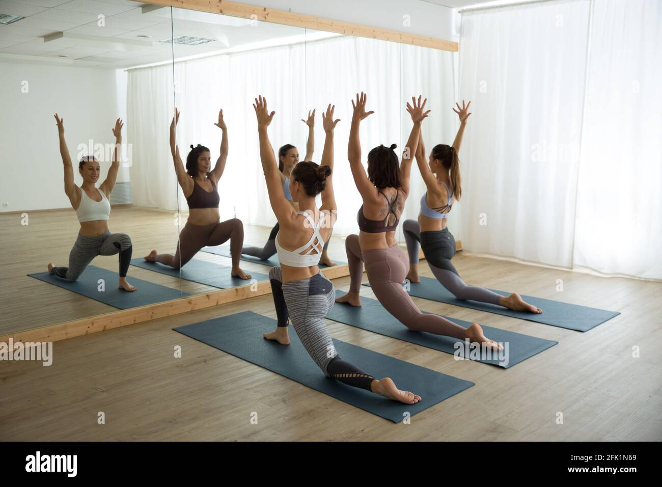 Groupe de jeunes femmes sportives en studio de yoga, pratiquant le yoga pose devant le miroir. Un style de vie sain et actif, en salle de gym Banque D'Images