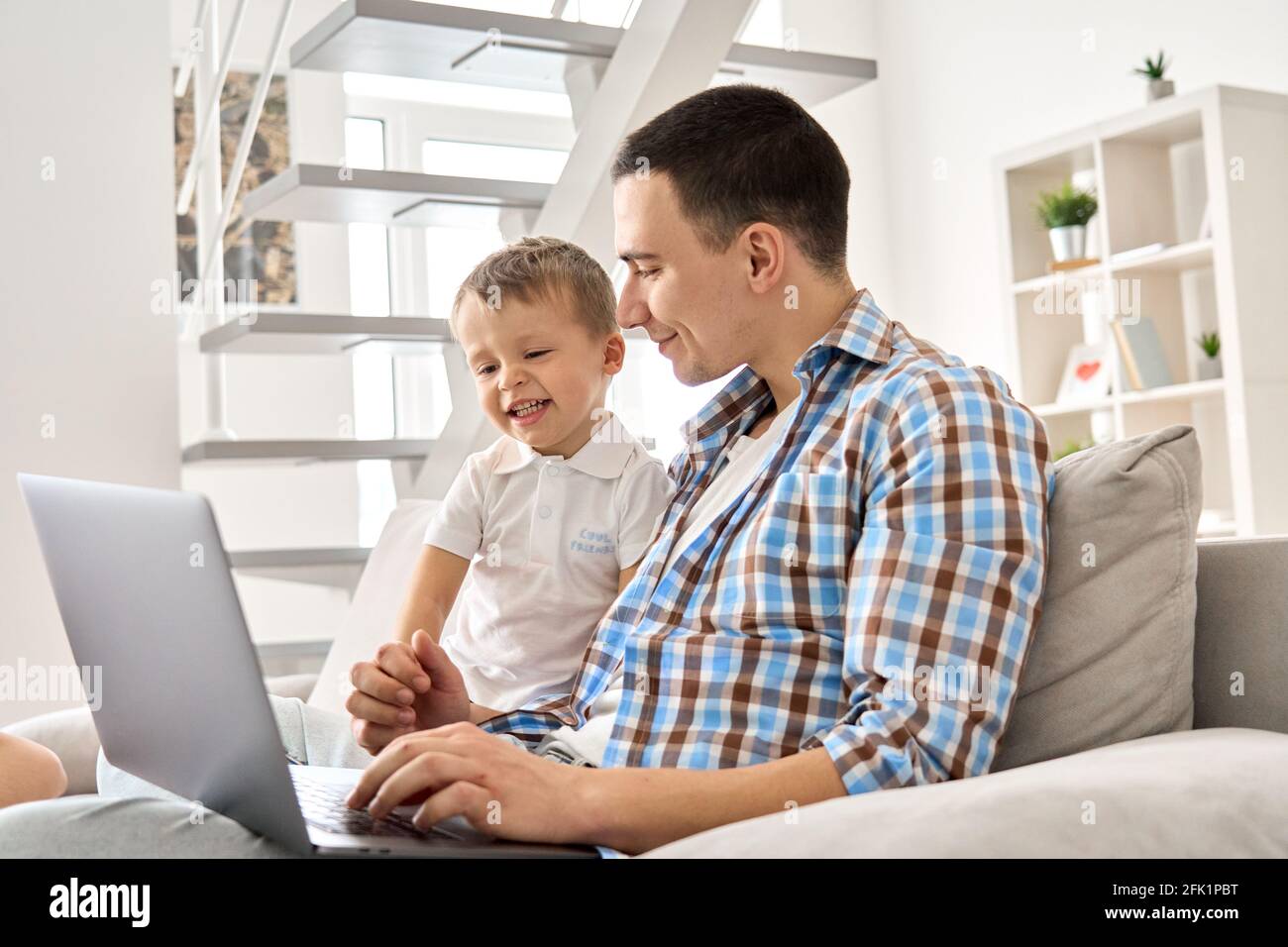 Un jeune père heureux et un enfant tout-petit fils mignon utilisant un ordinateur portable à la maison. Banque D'Images
