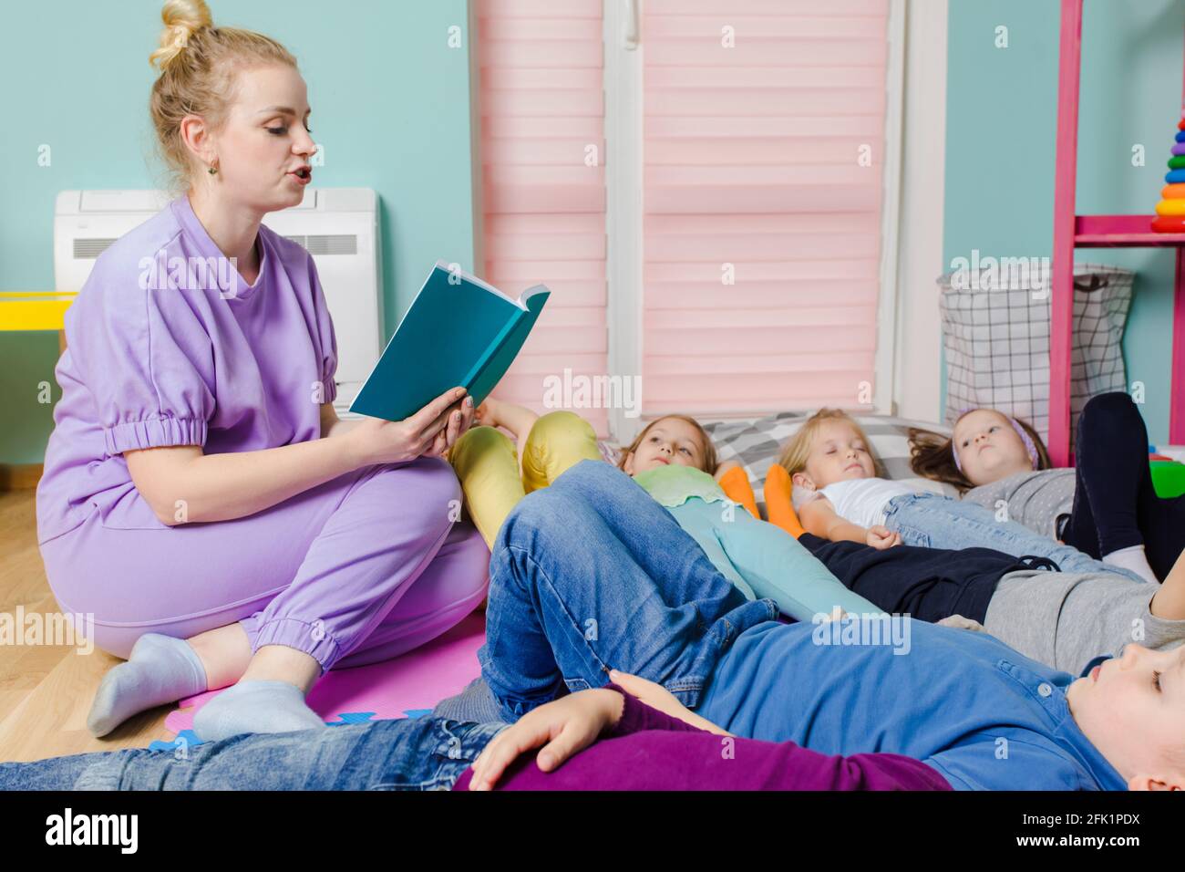 Les enfants actifs s'assetent sur des oreillers et des tapis moelleux à la maternelle Banque D'Images