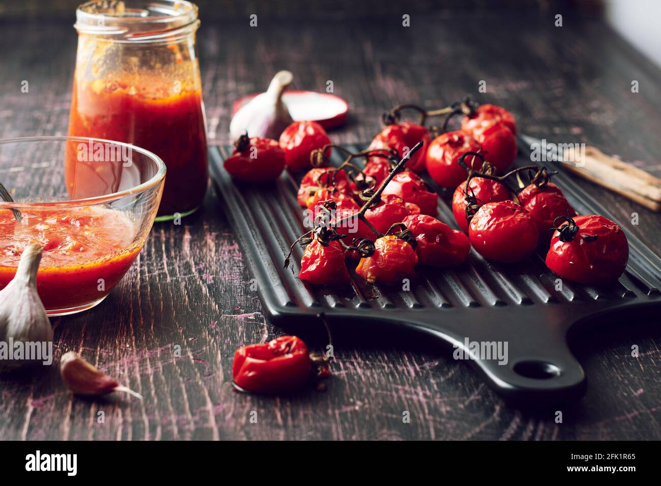 Tomates cerises grillées pour la sauce sur fond sombre. Banque D'Images