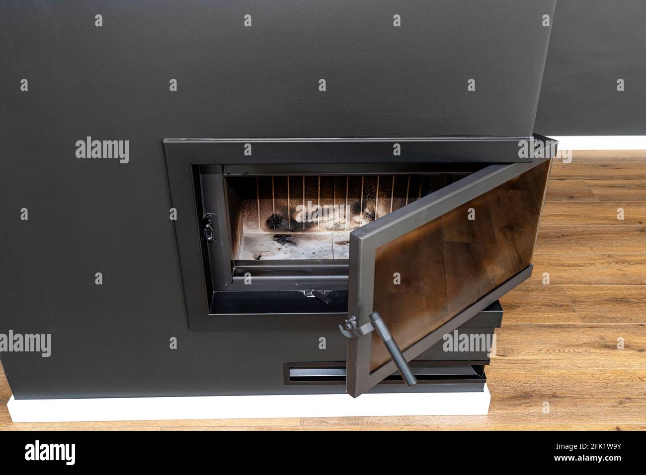 Panneau d'angle ouvert et sale dans une cheminée moderne avec une chambre de combustion fermée dans la salle de séjour, peinte en noir. Banque D'Images