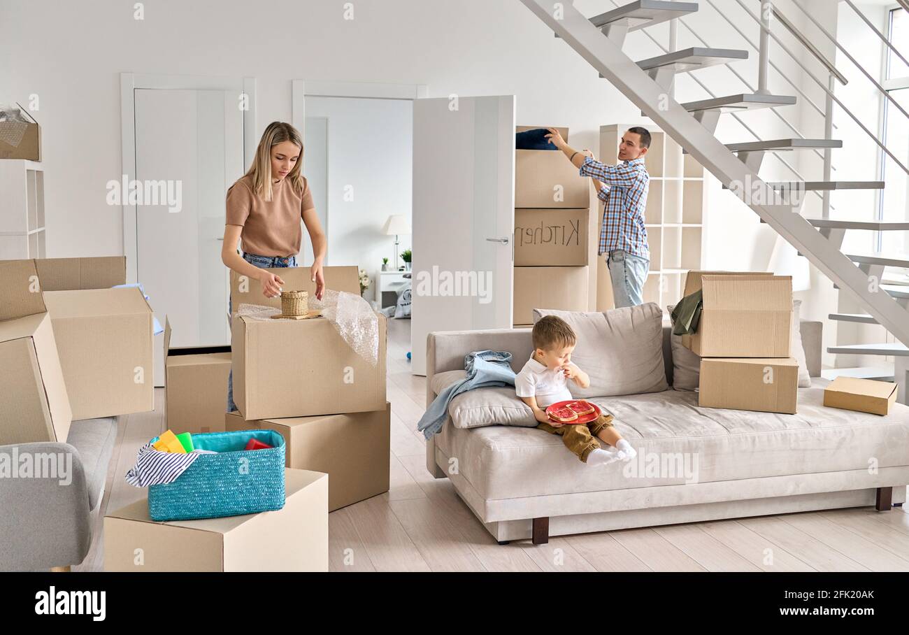 Jeune couple avec un enfant à la maison déballant les boîtes après avoir déménagé. Banque D'Images