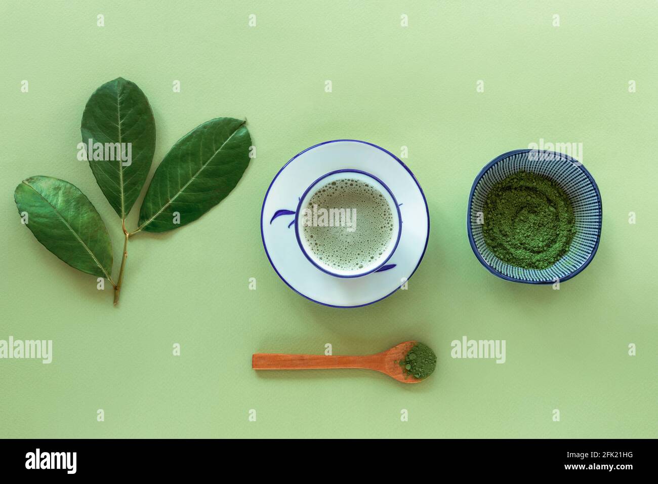 Thé vert matcha dans une tasse blanche, thé en poudre et cuillère en bois, vue du dessus. Boisson saine. Pose à plat. Banque D'Images