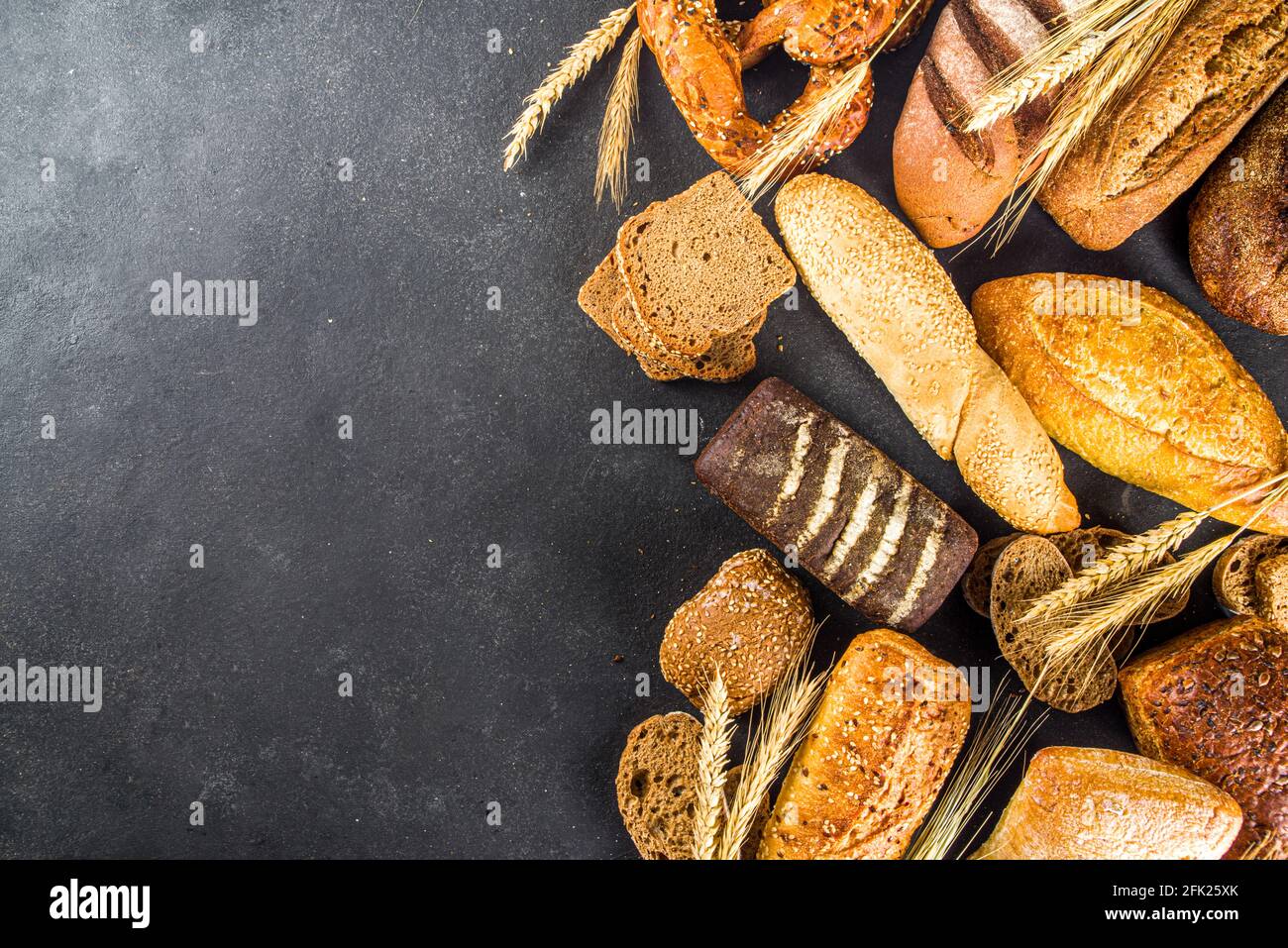 Assortiment de délicieux pains fraîchement cuits, sur fond de béton noir vue du dessus de l'espace de copie Banque D'Images