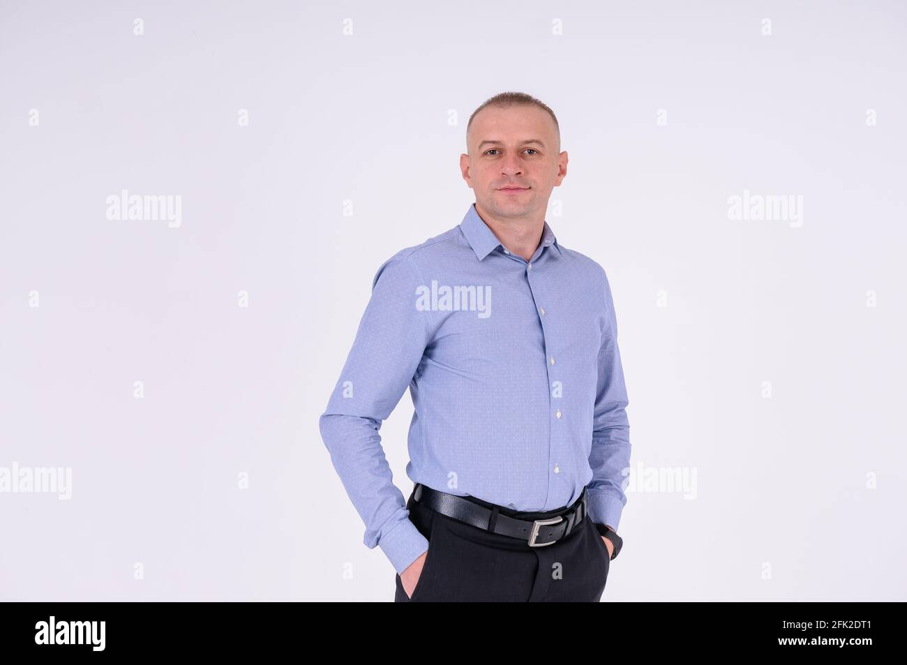 Un homme dans une chemise bleue et un pantalon noir sur fond blanc Banque D'Images