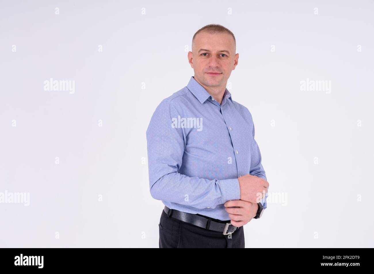 Un homme dans une chemise bleue et un pantalon noir sur fond blanc Banque D'Images