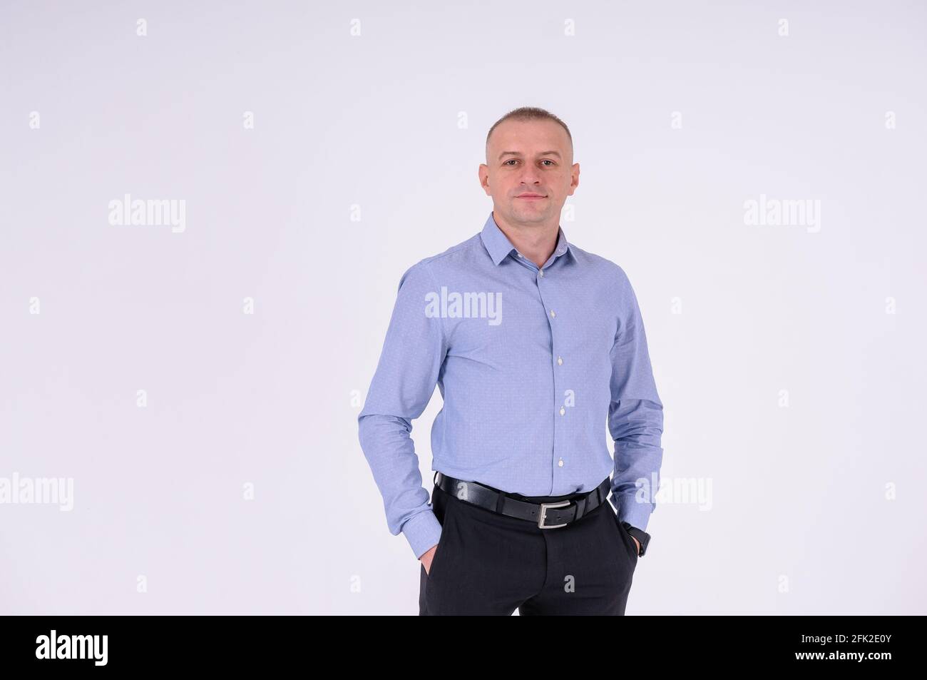 Un homme dans une chemise bleue et un pantalon noir sur fond blanc Banque D'Images