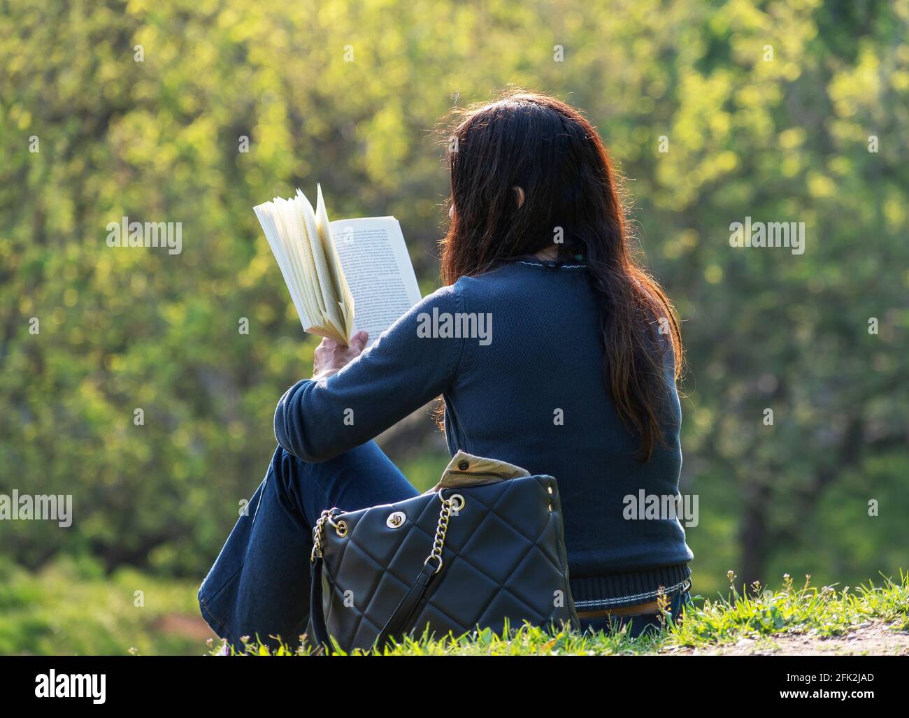 Femme lit un livre dans un parc de la ville Banque D'Images