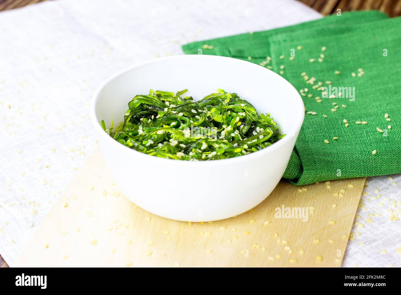 Salade d'algues vertes asiatiques dans un bol blanc sur fond de bois. Banque D'Images