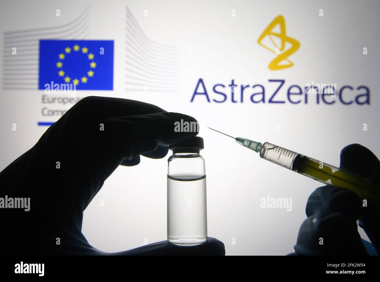 Dans cette illustration, une silhouette de mains en gants médicaux tient une seringue médicale et un flacon devant les logos d'AstraZeneca et de la Commission européenne (ce). Banque D'Images