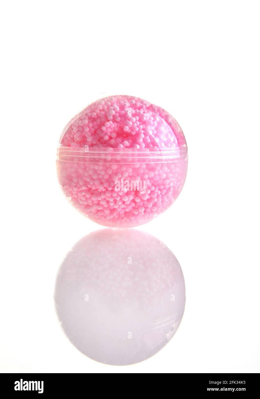 Boule transparente avec beaucoup de petites boules roses à l'intérieur, jouet pour enfants isolé sur fond blanc Banque D'Images