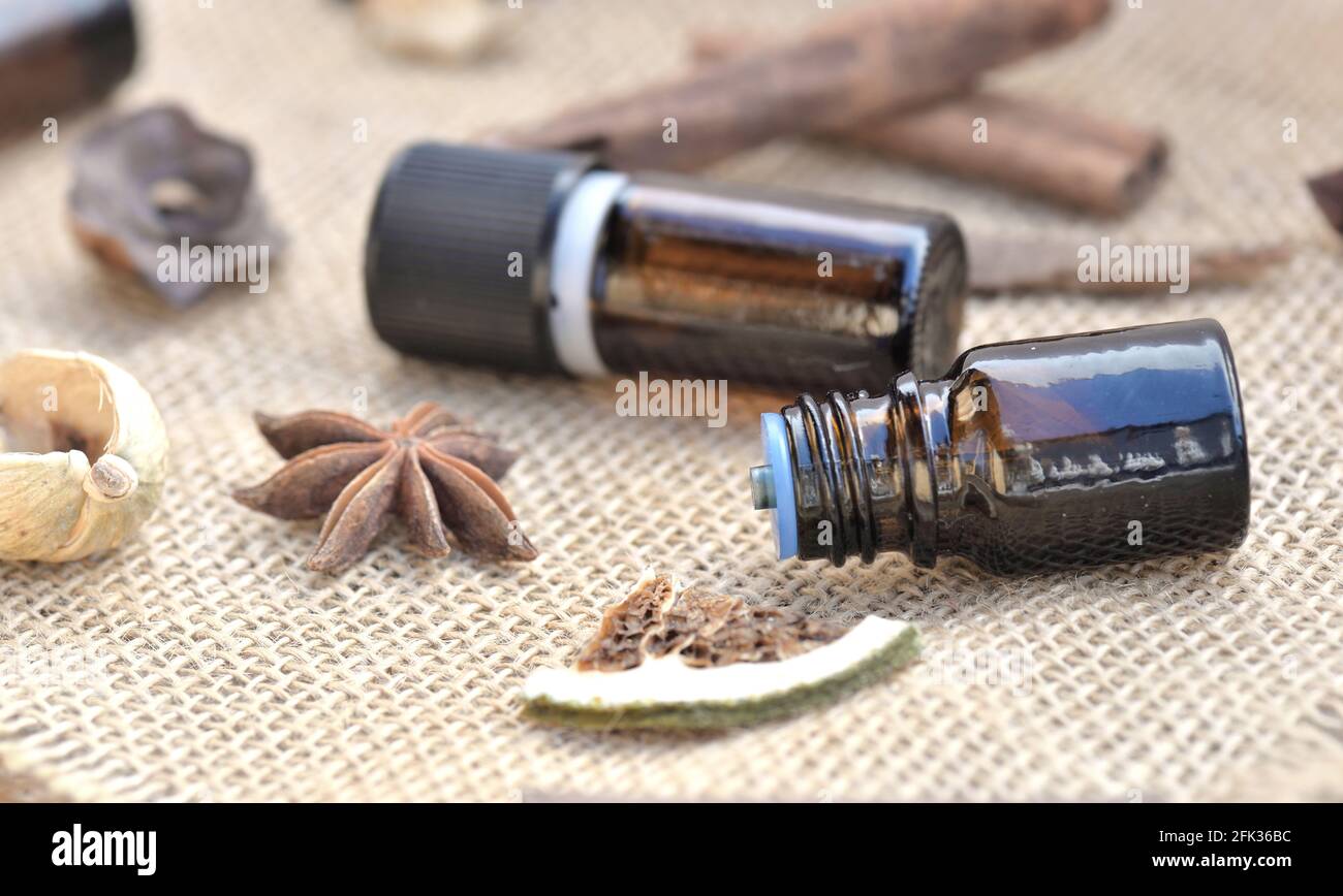 bouteilles d'huile essentielle avec bâton de cannelle, badian et fruits secs avec coquille sur un fond de tissu naturel Banque D'Images